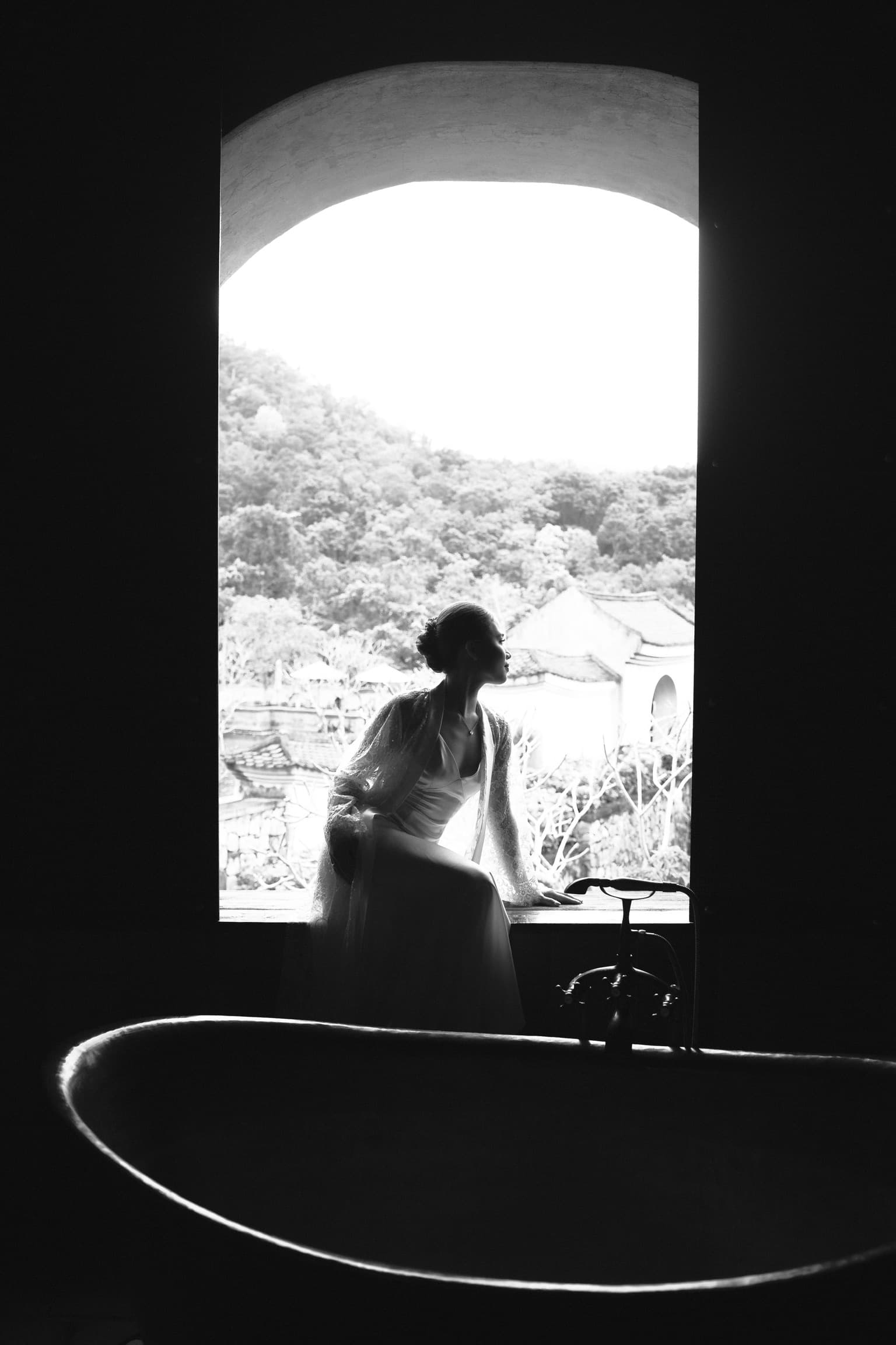 Black and white portrait of a woman beside a window.